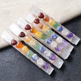 A collection of wands with various colorful crystals attached to them, displayed on a textured surface.
