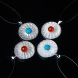 Four round flower pendants in silver frames on black cords.