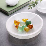 A white mineral bowl with a smooth, polished surface, containing Assorted colorful crystal beads.