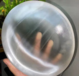 A close-up view of a person holding a large, smooth satin spar bowl.