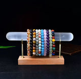 A polished wand holding multiple gemstone bracelets.