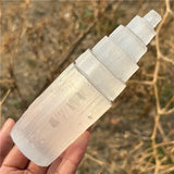 A hand holding a raw satin spar pinnacle spire to show its stepped design.