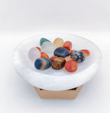 A shallow, round white gypsum bowl rests on a small brown cardboard hex stand against a white backdrop.