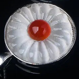 A white crystal flower pendant with a red centre.