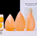 Three smooth polished orange tear drop shape gypsum mineral.