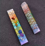 Two rainbow aura wands with embedded crystals. It is wrapped in copper wire on a black background.